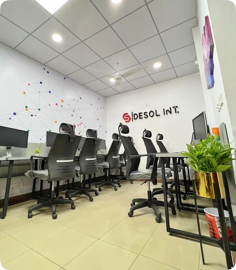 Modern office with computers, gray chairs, geometric wall art, and "Desol Int." logo.